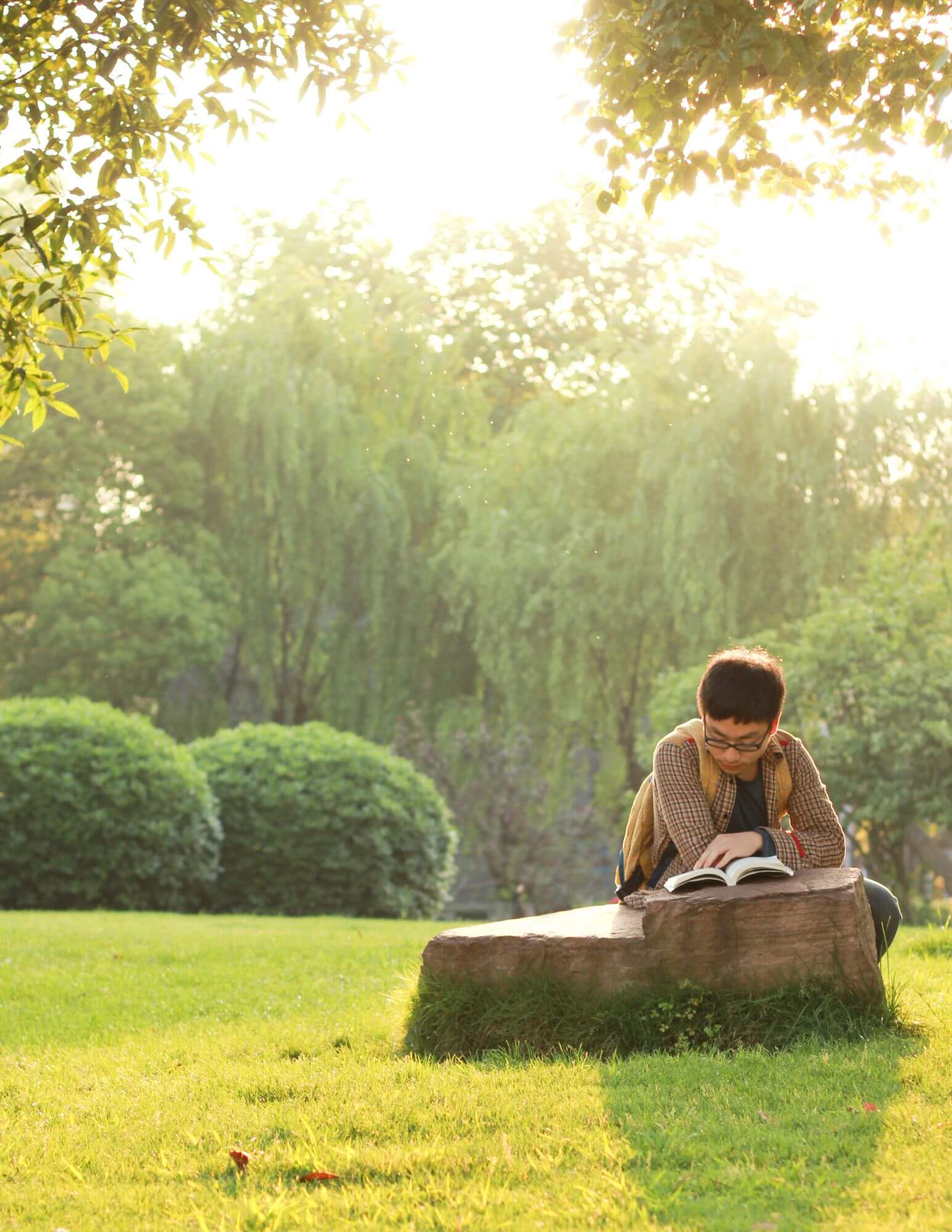 A man sitting outdoors reading a book
