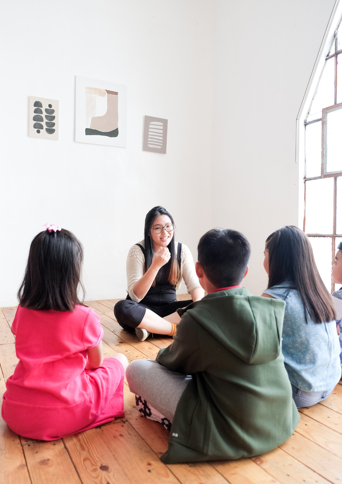 A teacher and small group of children gathered in a circle on the floor