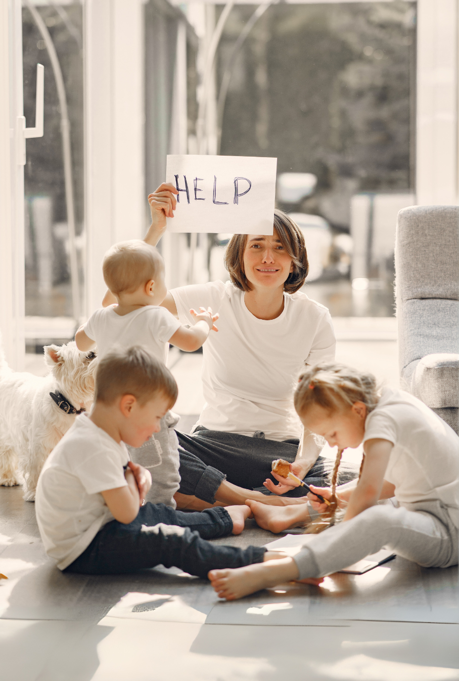 A parent surrounded by children holds up a sign for help.