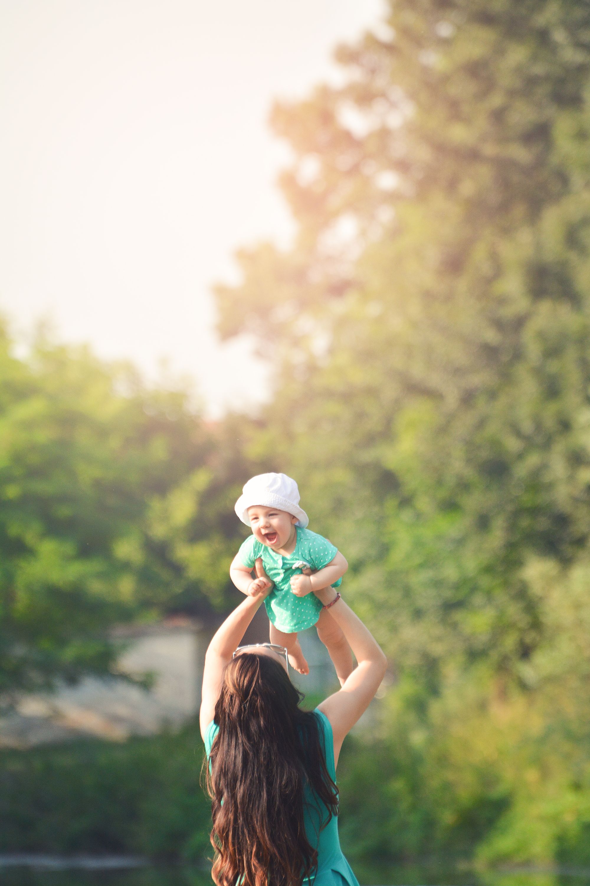 A mother lifting her baby up above her head