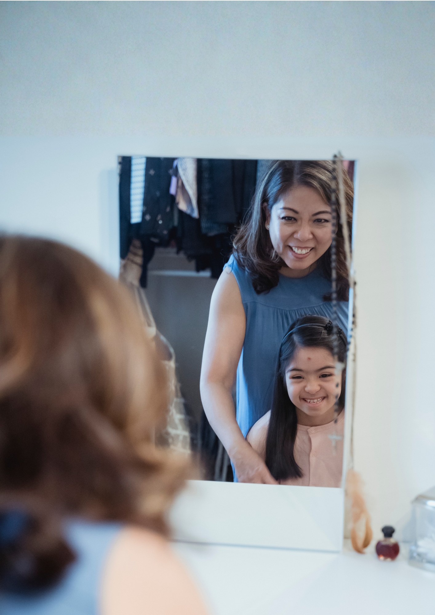 A mother and daughter look in a mirror