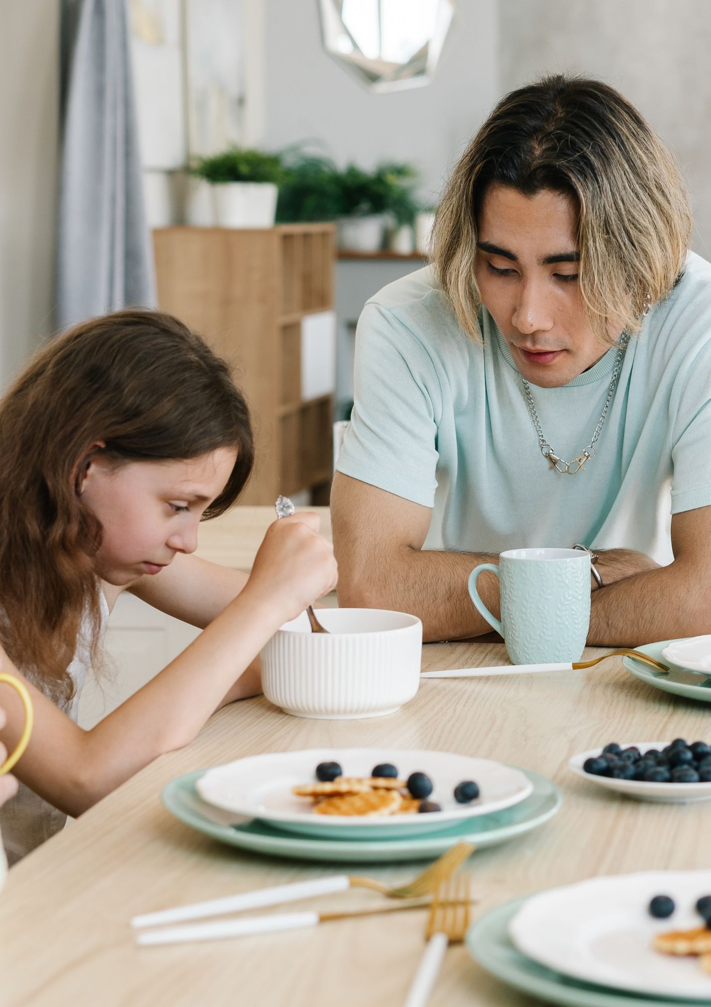 A teenager talks to his sister at the kitchen table