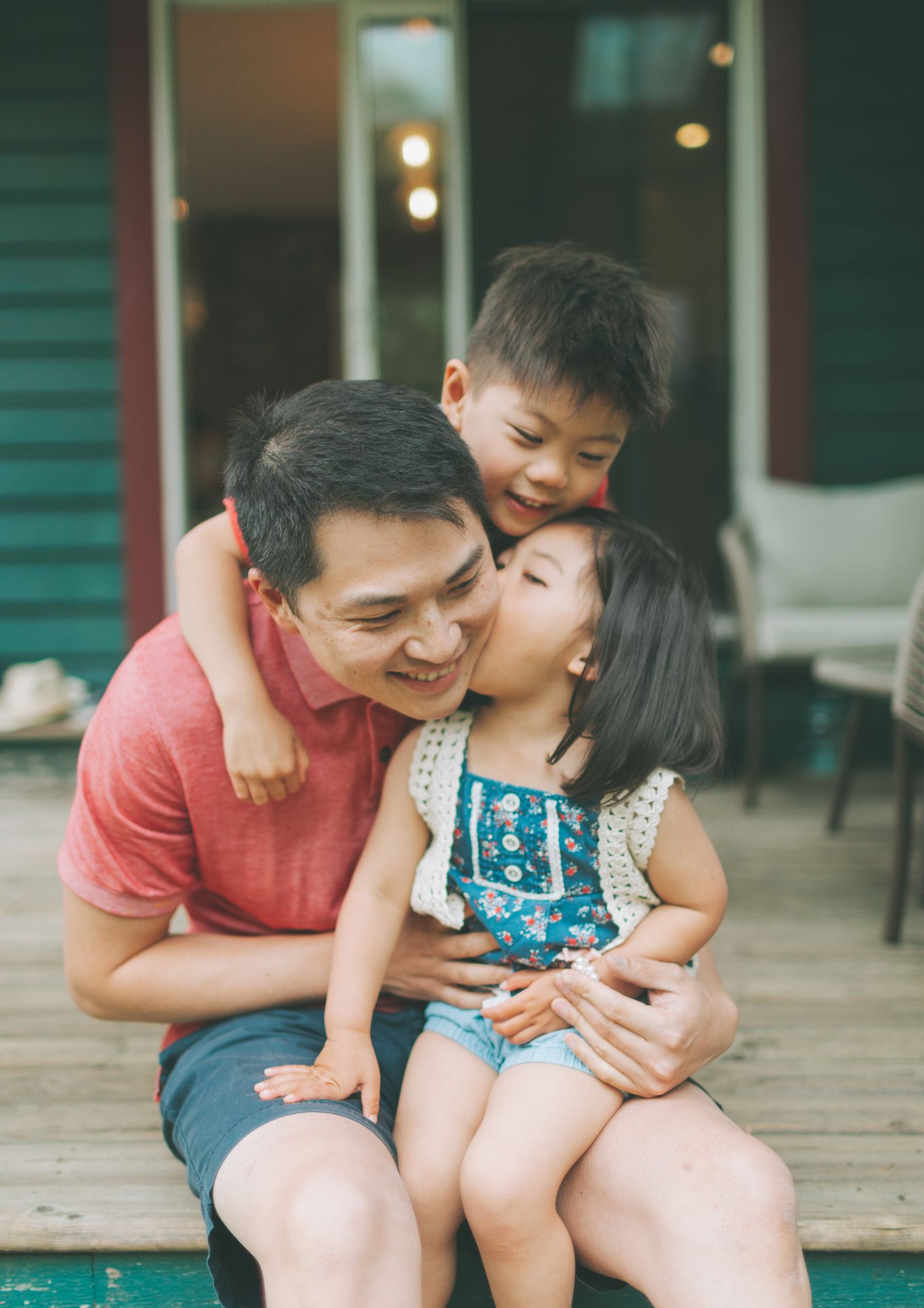 Two children hug their father
