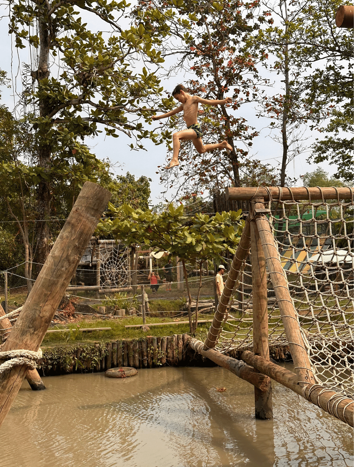 A child leaping across a muddy puddle at Get Growing Community Farm