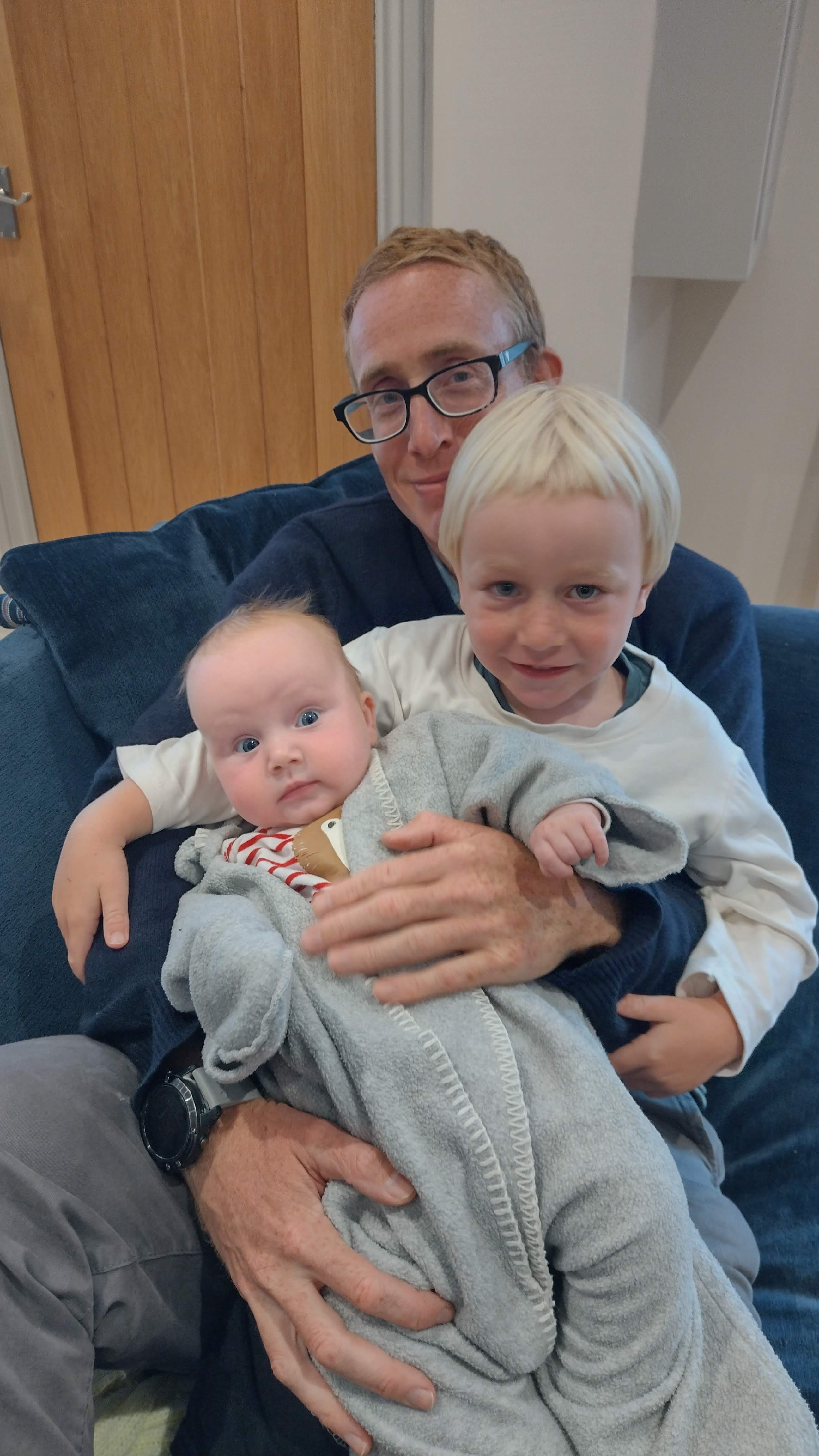 Two children sit on their father.