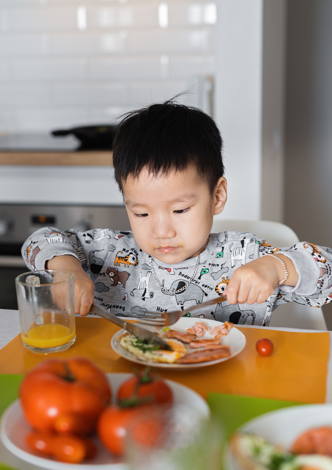 An Asian toddler eats a meal in their highchair