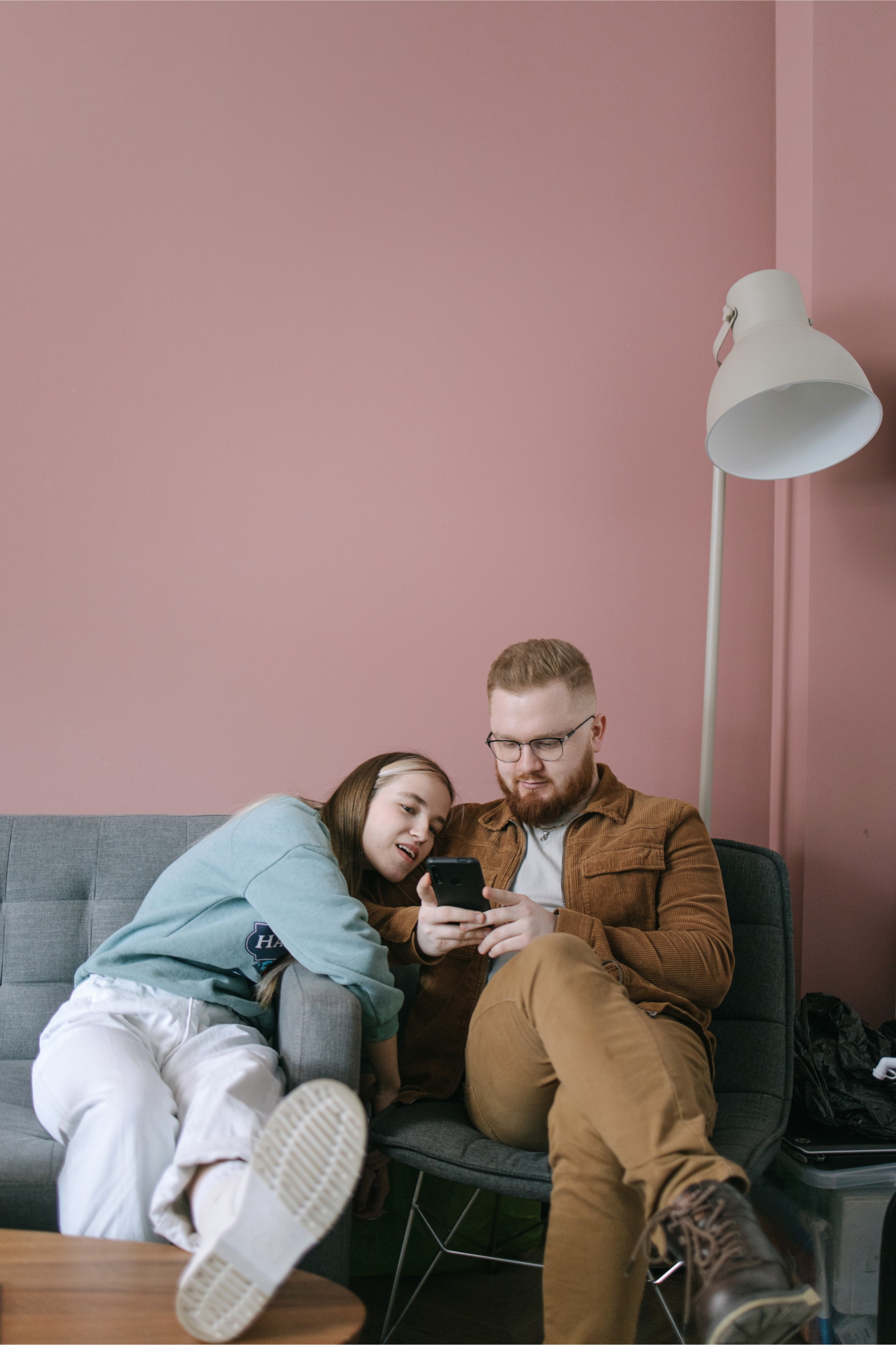 A couple sit on a couch looking at their phones