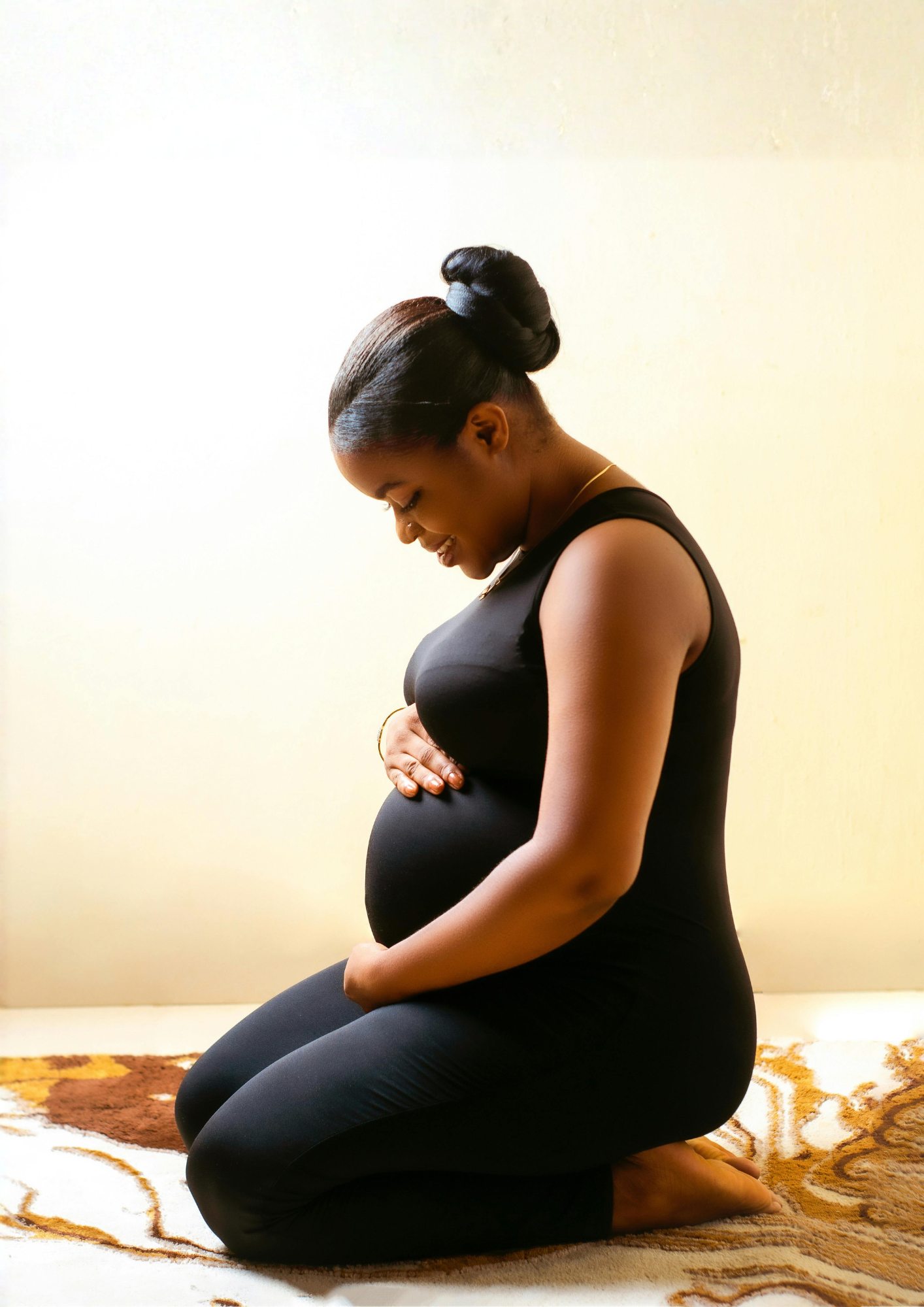A pregnant woman Kneels holding her stomache