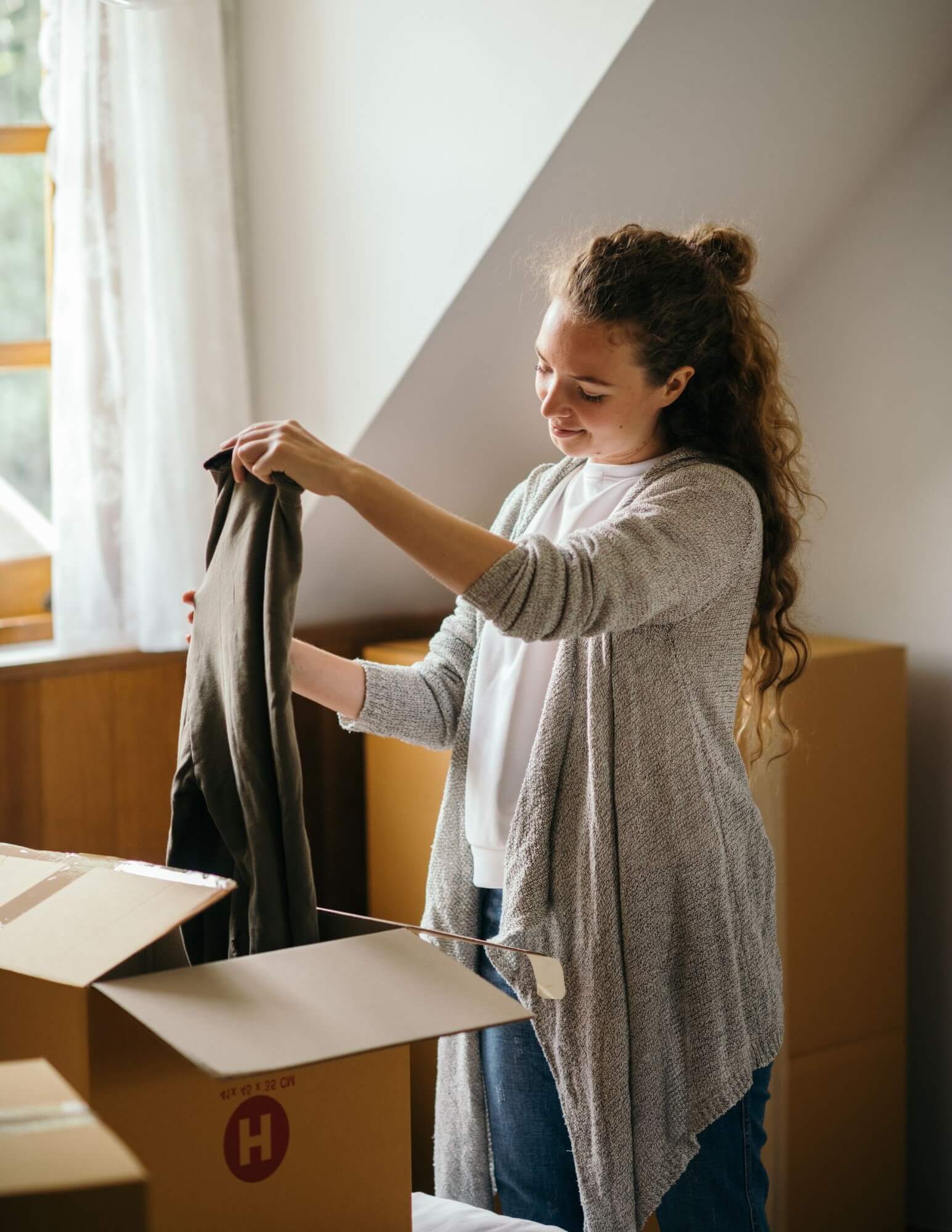 A White woman packing clothes into a moving box