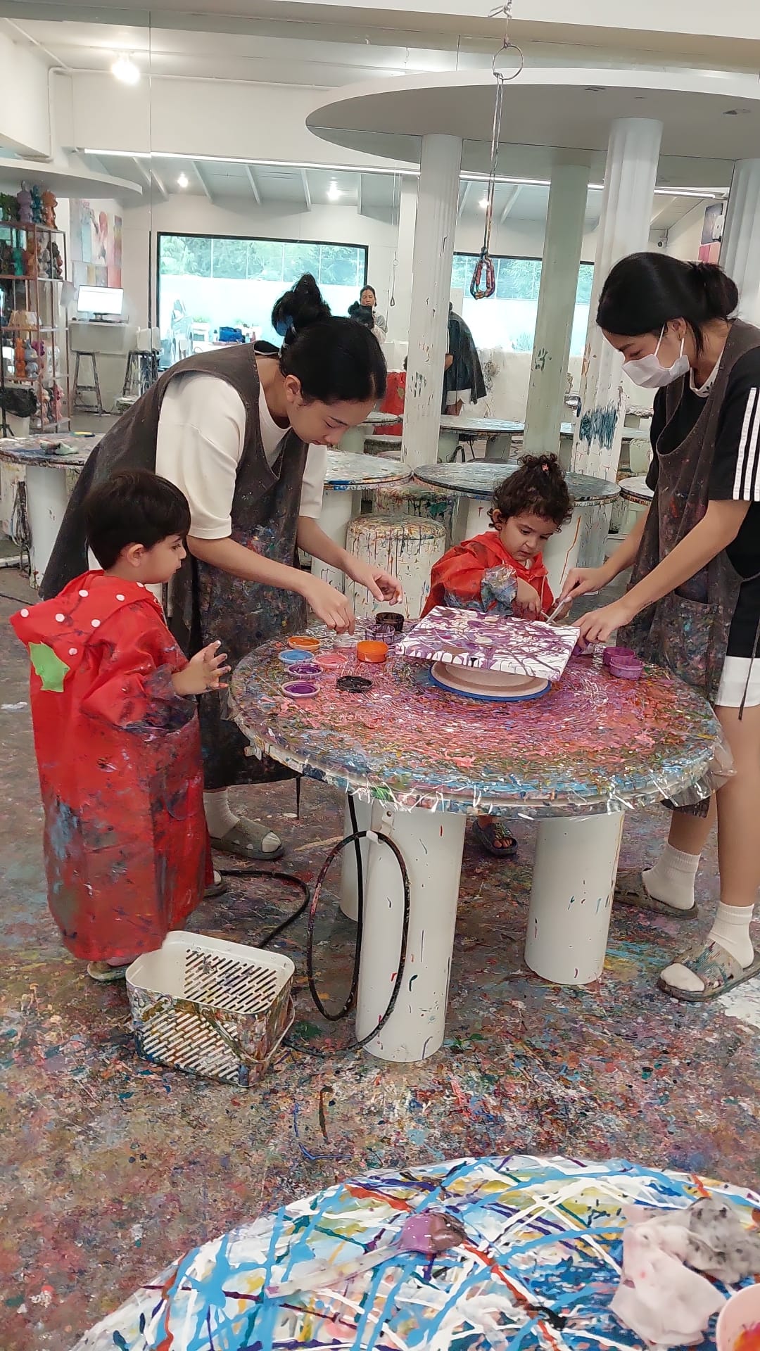 Two messy children painting watched by two adults
