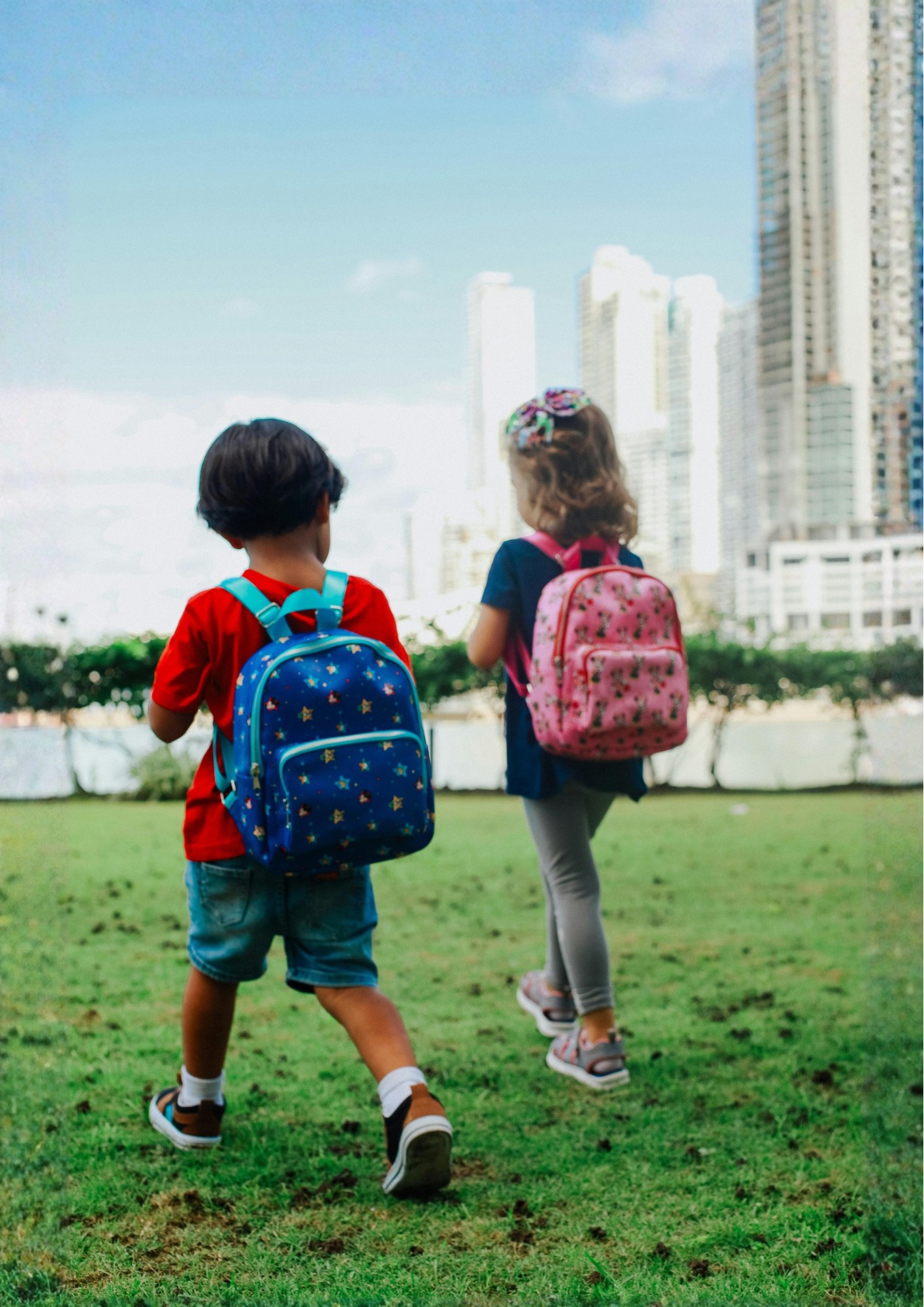 Two children walk across some grass