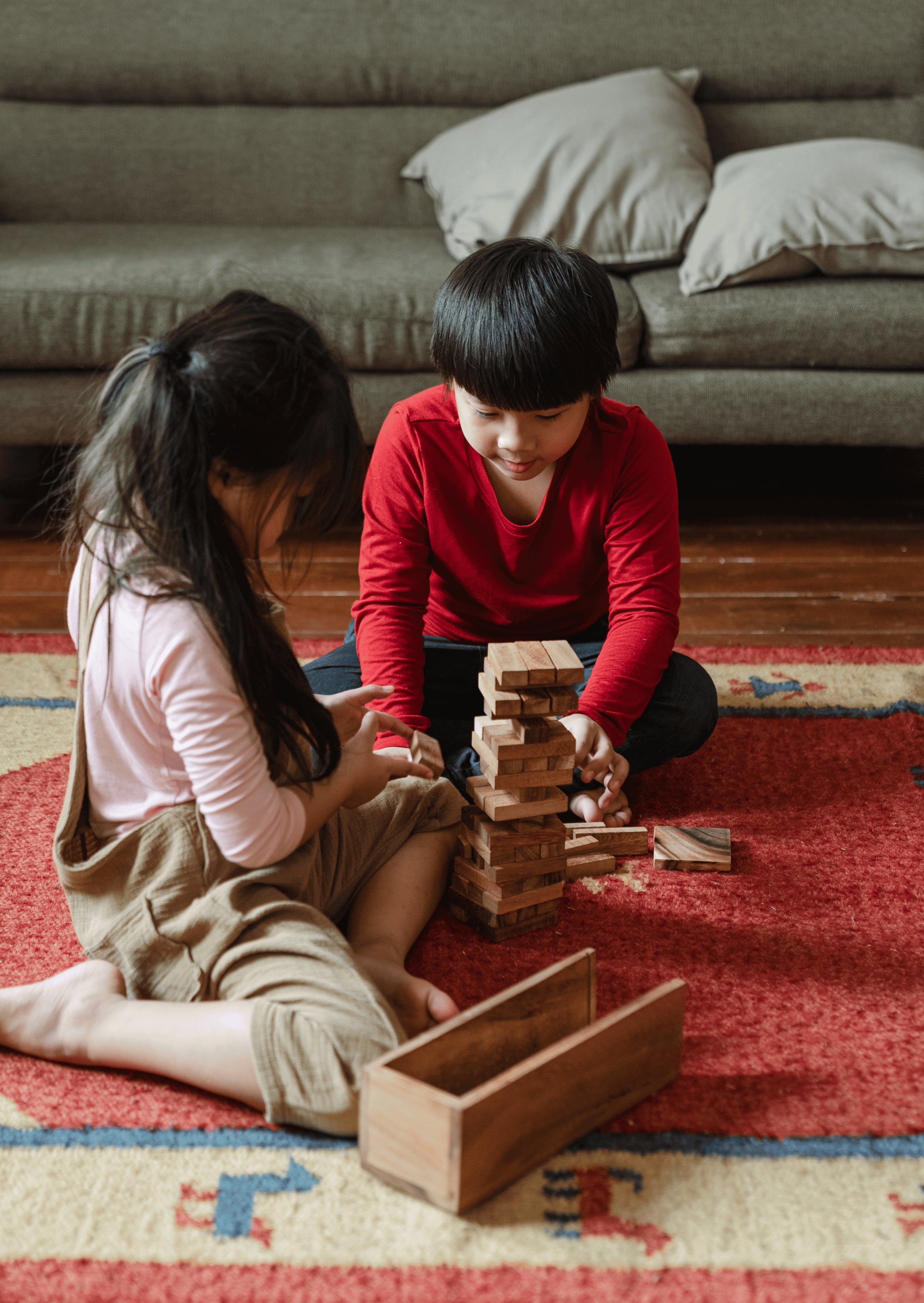 Two Asian children playing JENGA on the floor