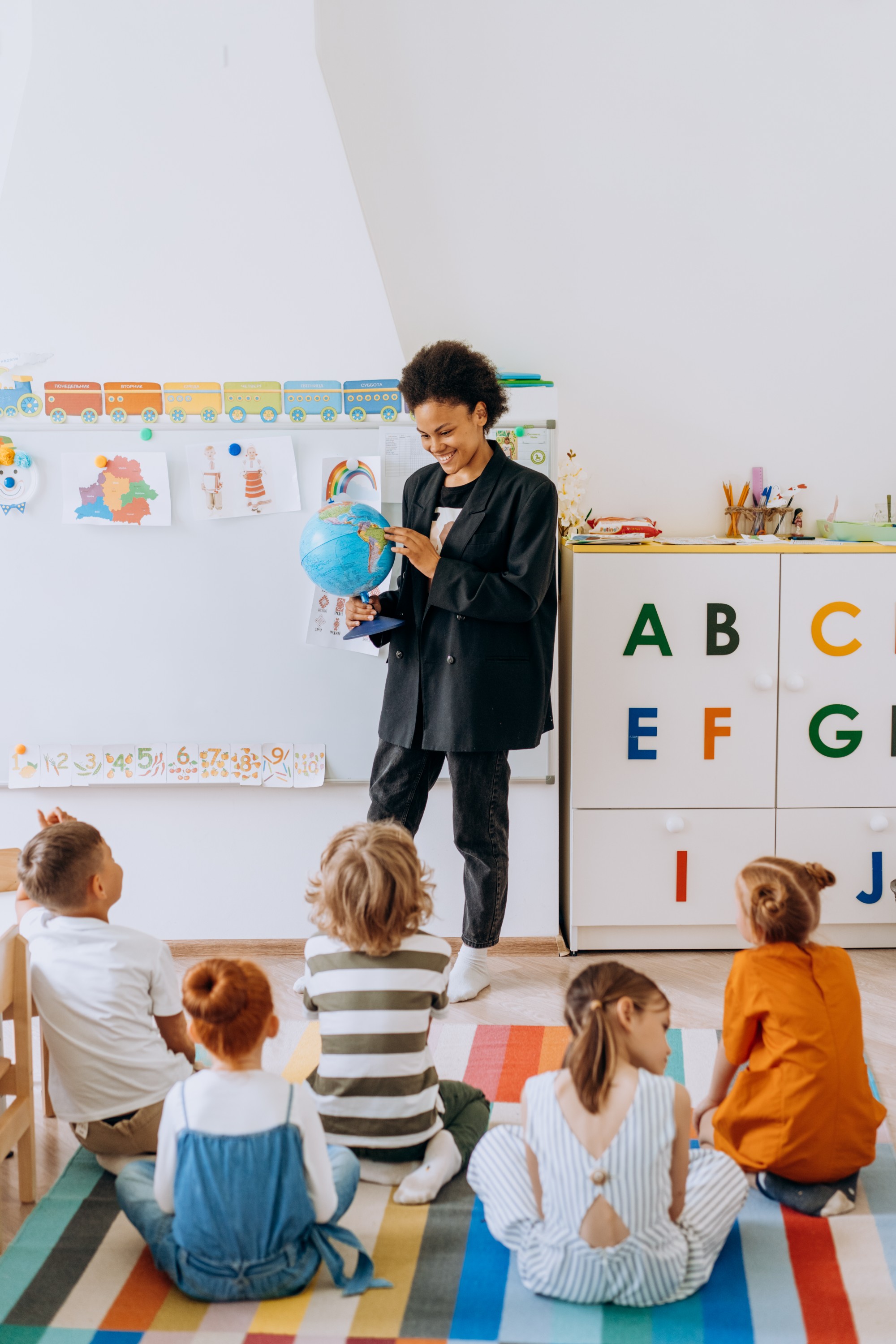 A teacher holds a globe at the front of a classroom