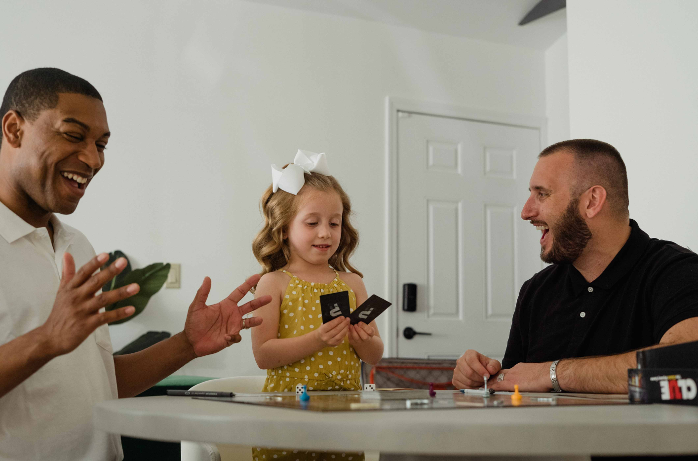 A young girl plays a boardgame with her fathers