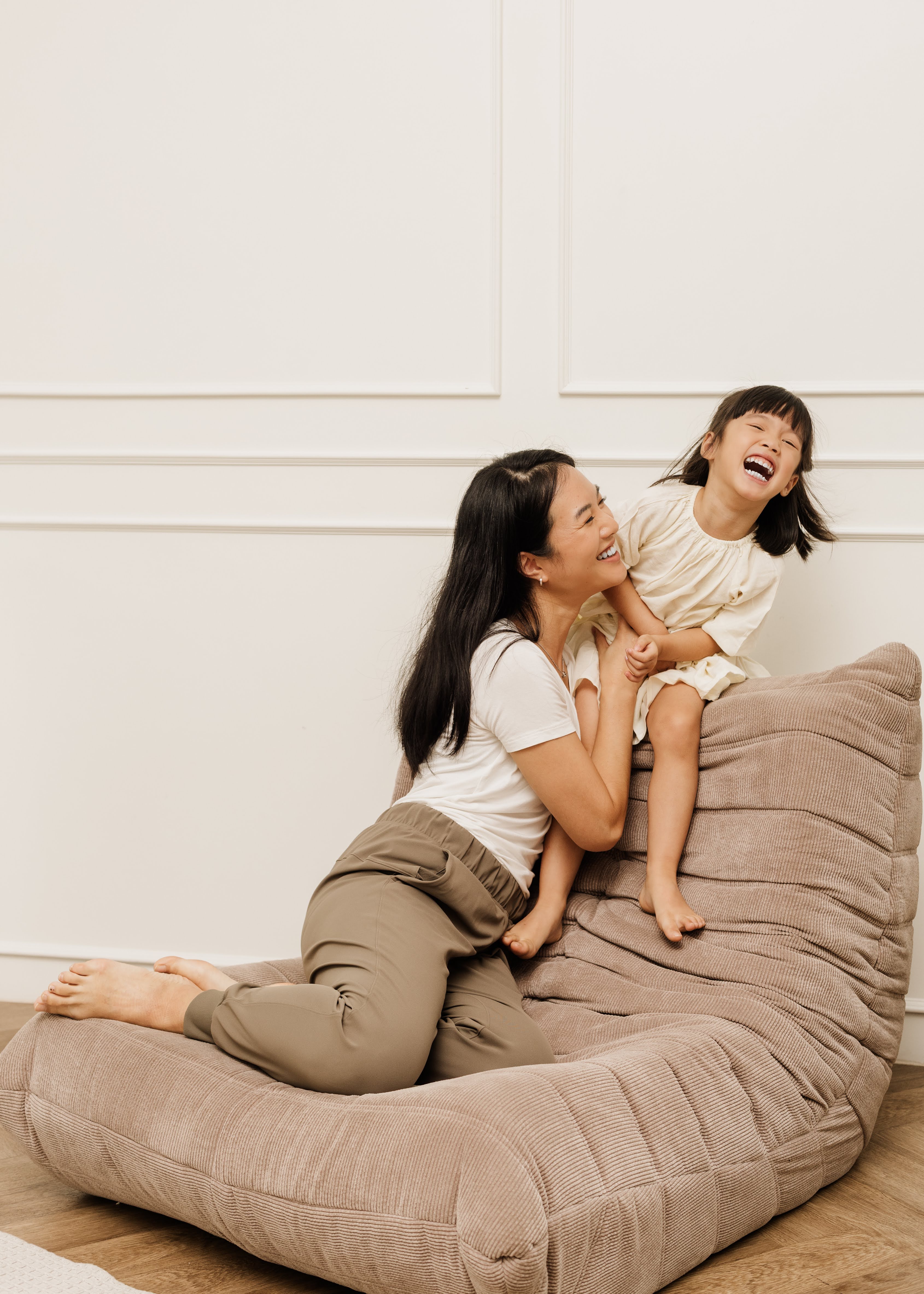 A mother and daughter play on a couch