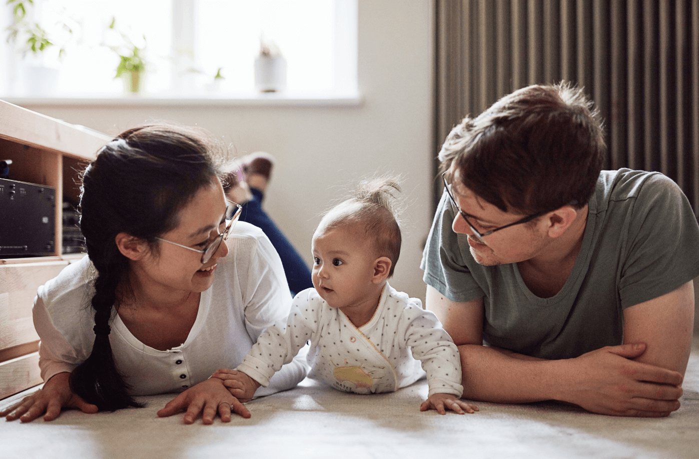 A mother, father and baby all lying on their tummies and interacting
