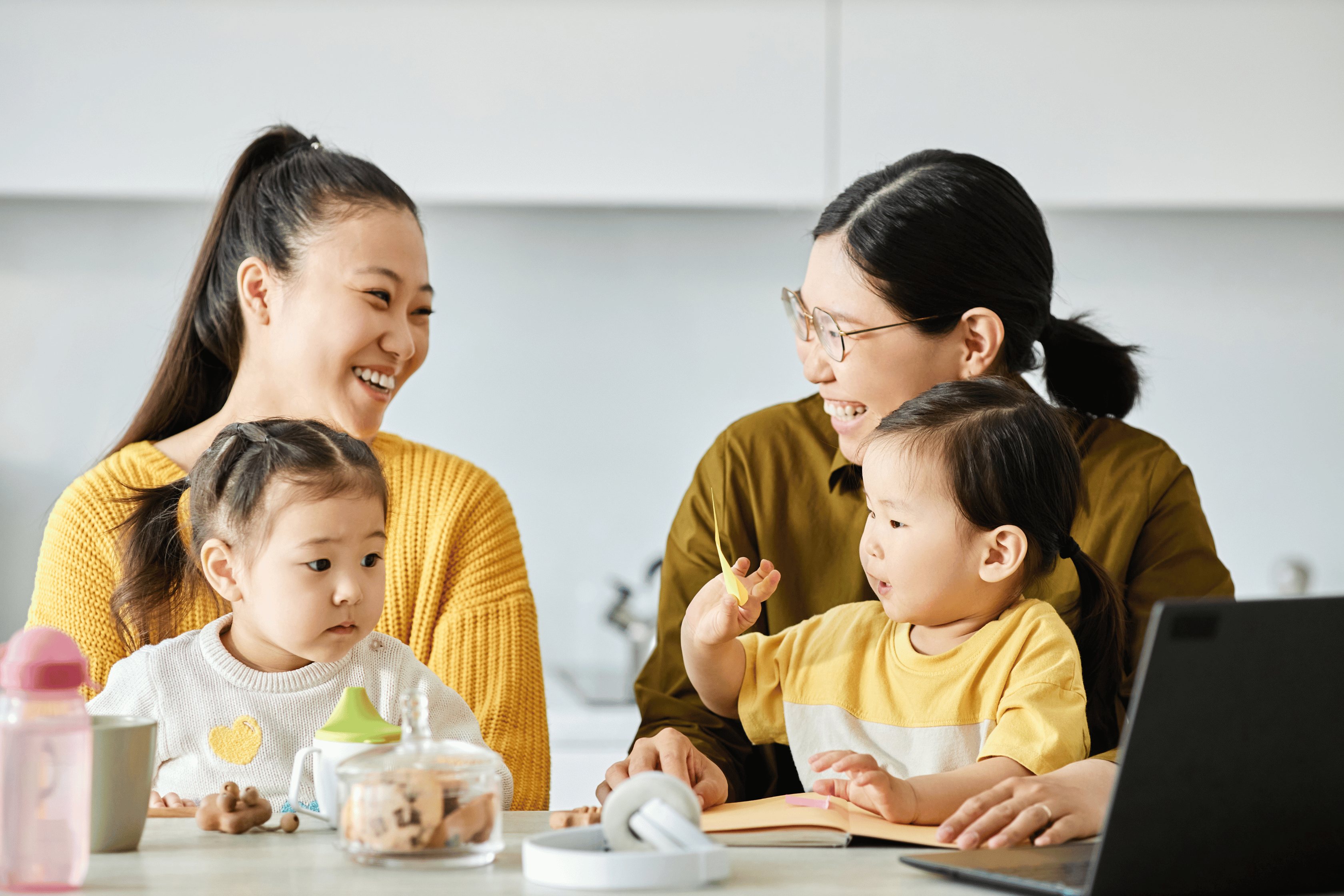 Two Asian women laughing together with their toddlers