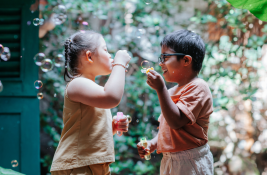 Two children play with bubbles outdoors