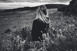 A black and white lady stands in a field