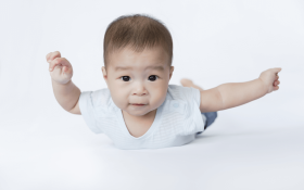 An Asian baby balancing on their tummy