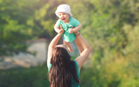 A mother lifting her baby up above her head