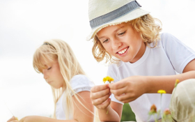 Two white tweens crouching in a field of daisies