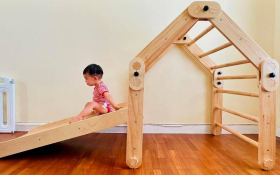 A toddler on an indoor wooden climbing frame and slide