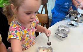 A white toddler attends a cooking class at Bumpsy Daisy Cafe in Bangkok