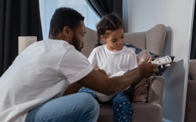 A dad teaching his daughter how to play guitar