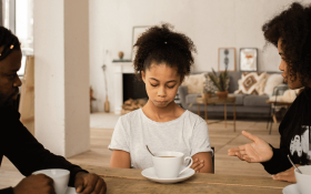 A teenage girl sits with her parents.