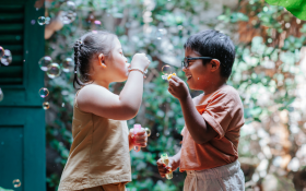 Two children play with bubbles outdoors