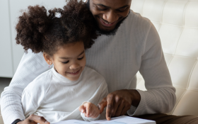 A Black father and his daughter read together