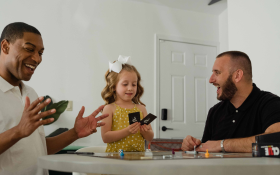 A young girl plays a board game with her fathers