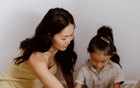 A mother and daughter sit on the floor together