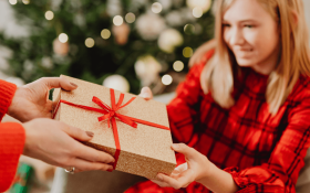 A girl in red accepts a Christmas present.