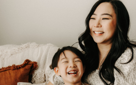 A mother and child cuddle on a sofa.