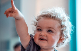 A toddler raises her hand