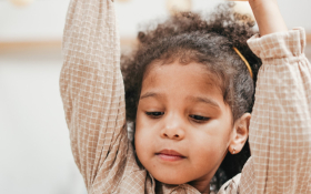 A child stretches their arms up.