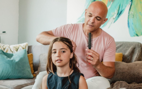 A father combs his daughter's hair.