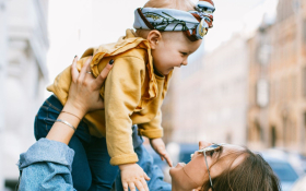 A mother holds her child high in the air.