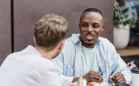 Two men chat at a cafe.