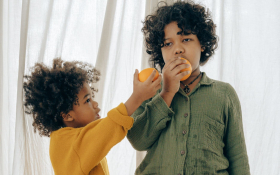 Two brothers eat oranges