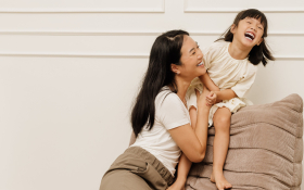 A mother and daughter play on a couch
