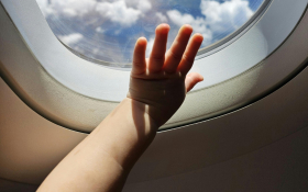 a child's hand pressed to an airplane window.