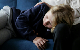 A child curls up on an adults lap