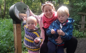 A mother and children crouch by a sign 