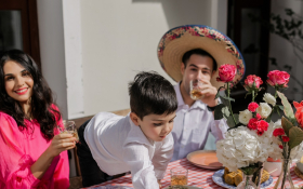 A boy at a party reaches across the dinner table
