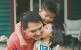 Two children kiss their father