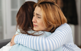 Two sorrowful women hug