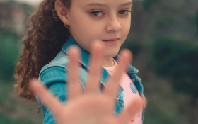 A young girl holds out her hand